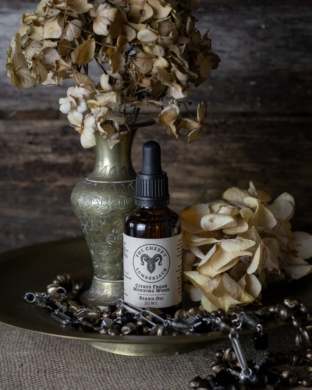 Bottle of brand oil on a decorative tray with dried flowers and a textured background