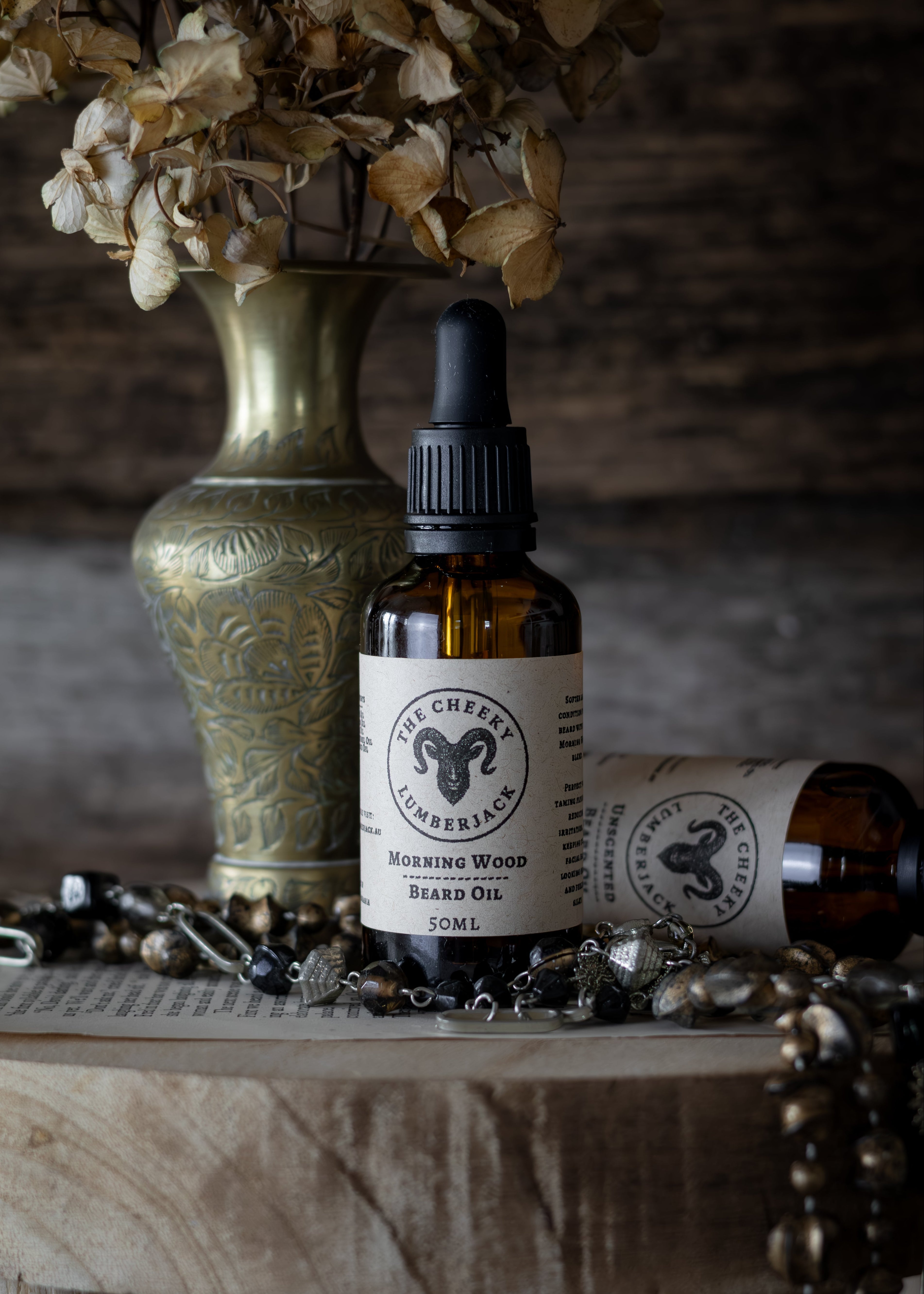 Two bottles of 'The Cheff' brand beard oil on a wooden surface with decorative elements.