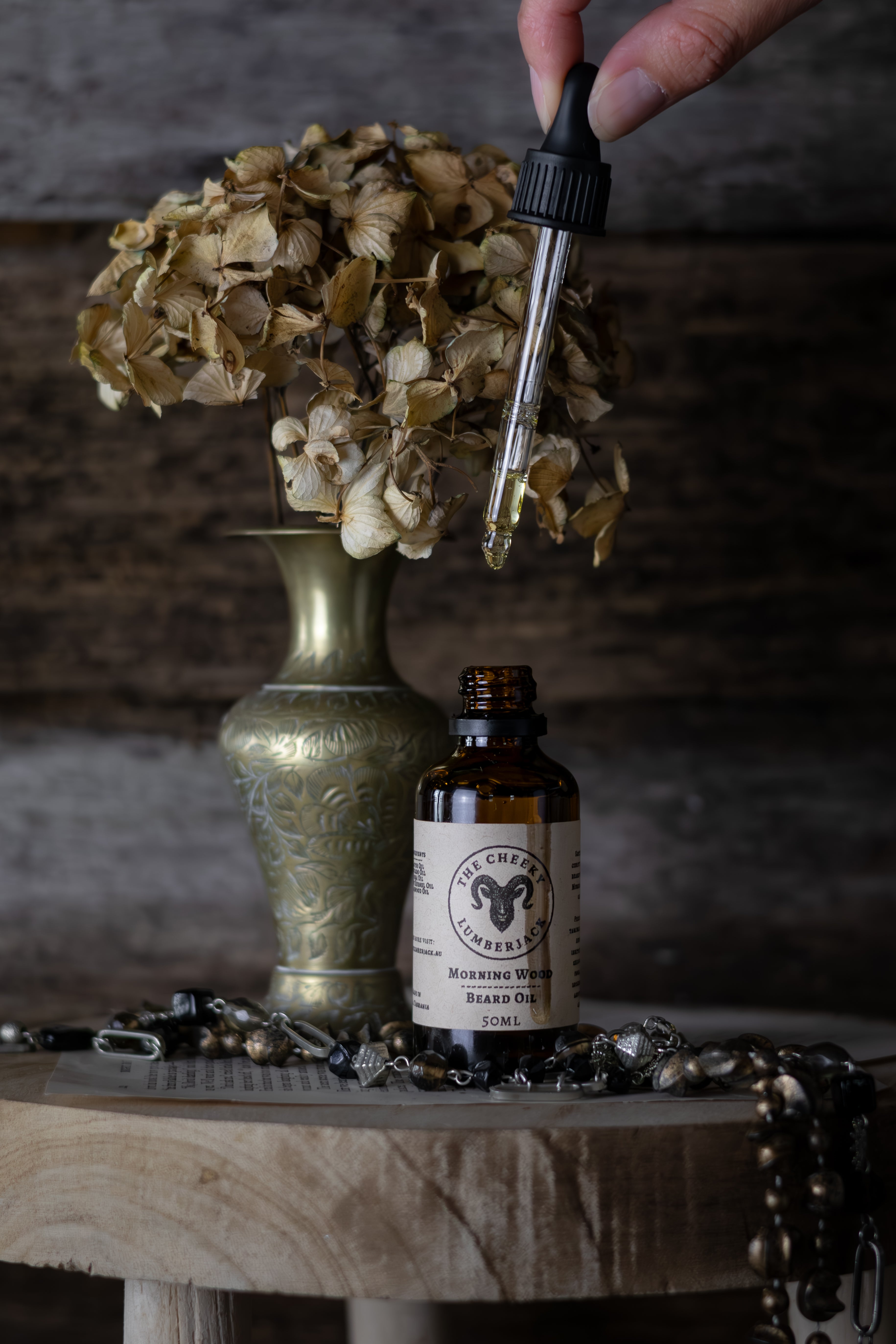 Bottle of alcohol with dropper and dried flowers on a wooden surface