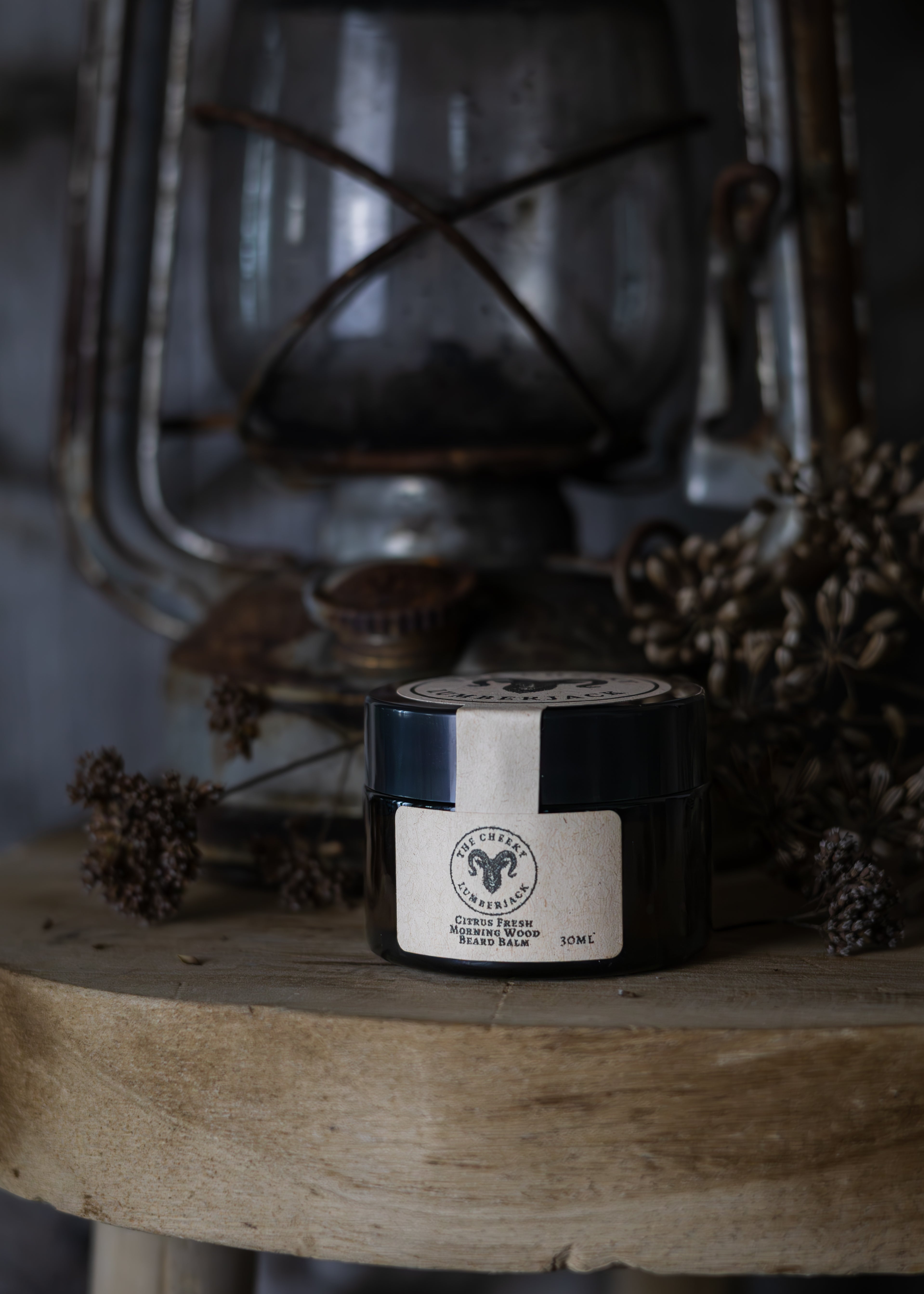 Jar of balm on a wooden surface with a vintage lantern in the background