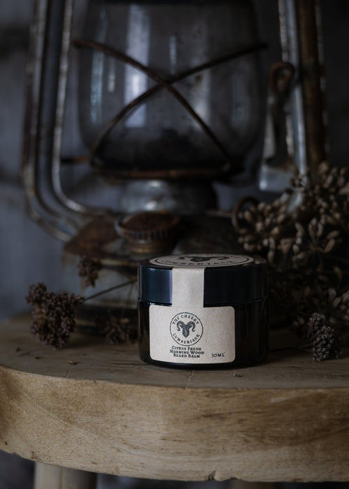 Jar of balm on a wooden surface with a vintage lantern in the background