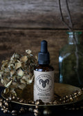 Bottle of 'The Cheeky Lumberjack' skin serum on a wooden surface with decorative elements.
