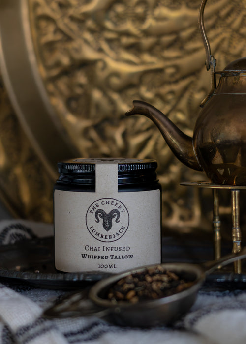 Jar of Chai Infused Whipped Balm with a brass teapot and spoon on a textured surface