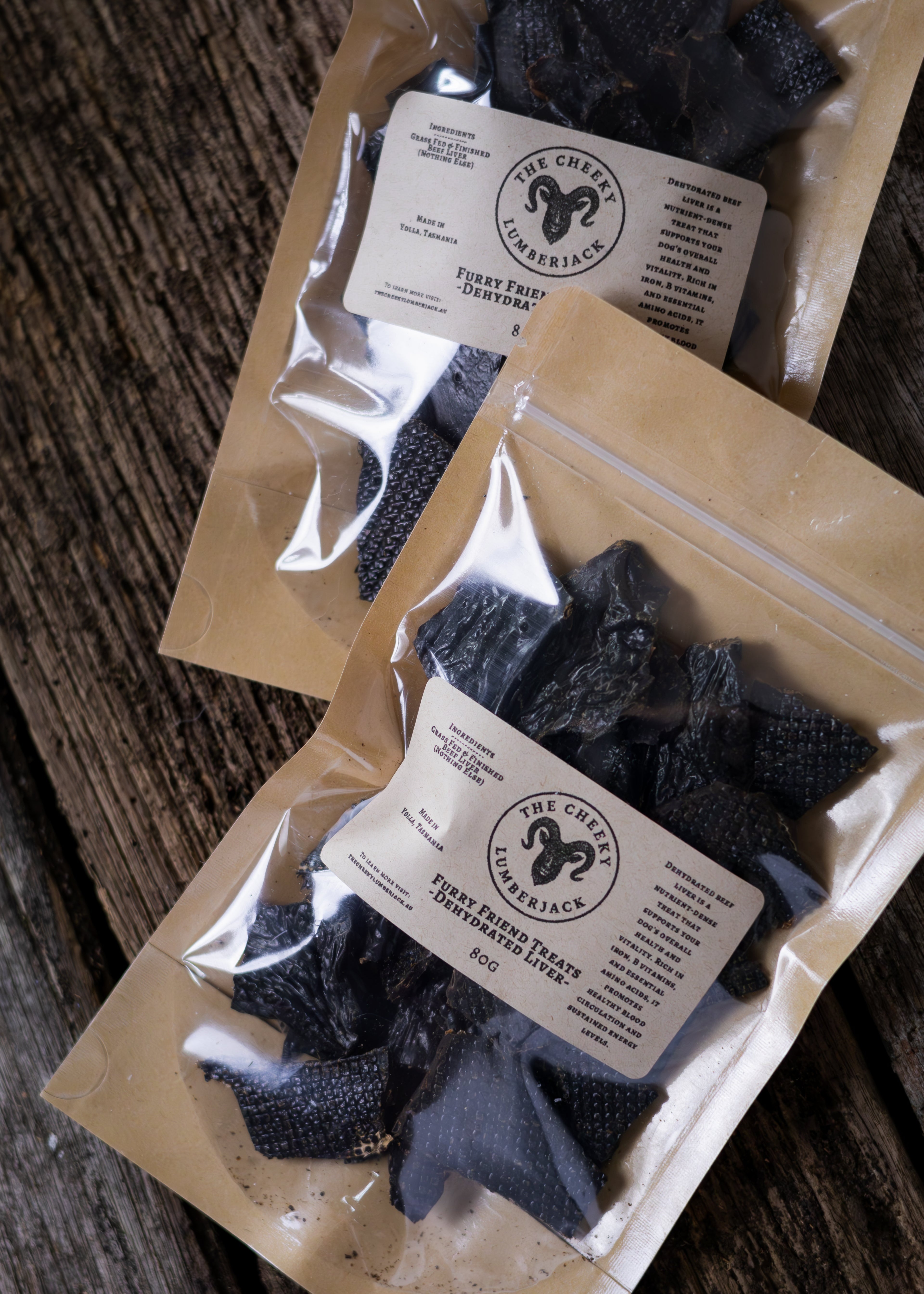 Two packages of dried beef liver with a label on a wooden surface