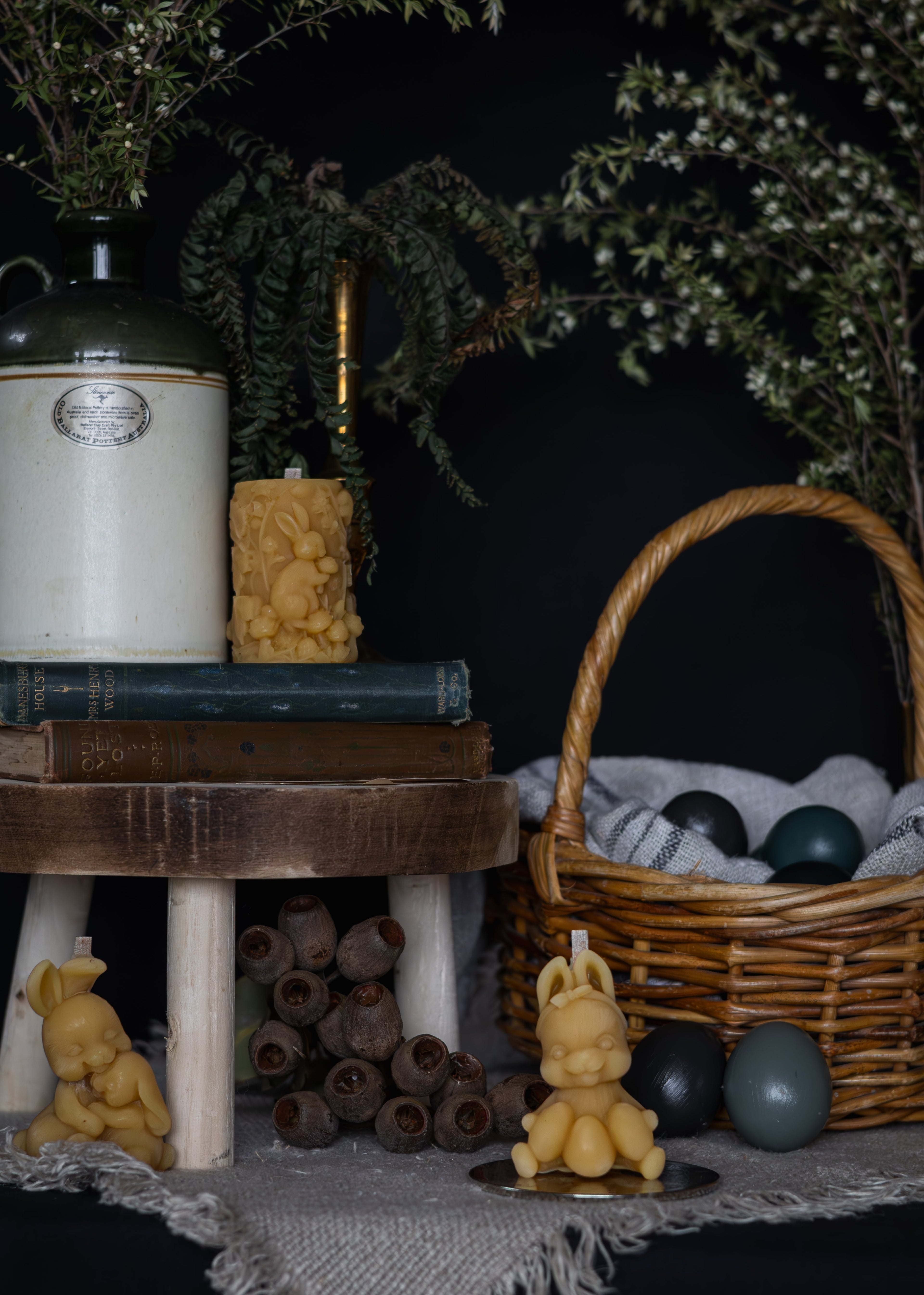 Decorative setting with candles, books, a basket, and decorative items on a dark background