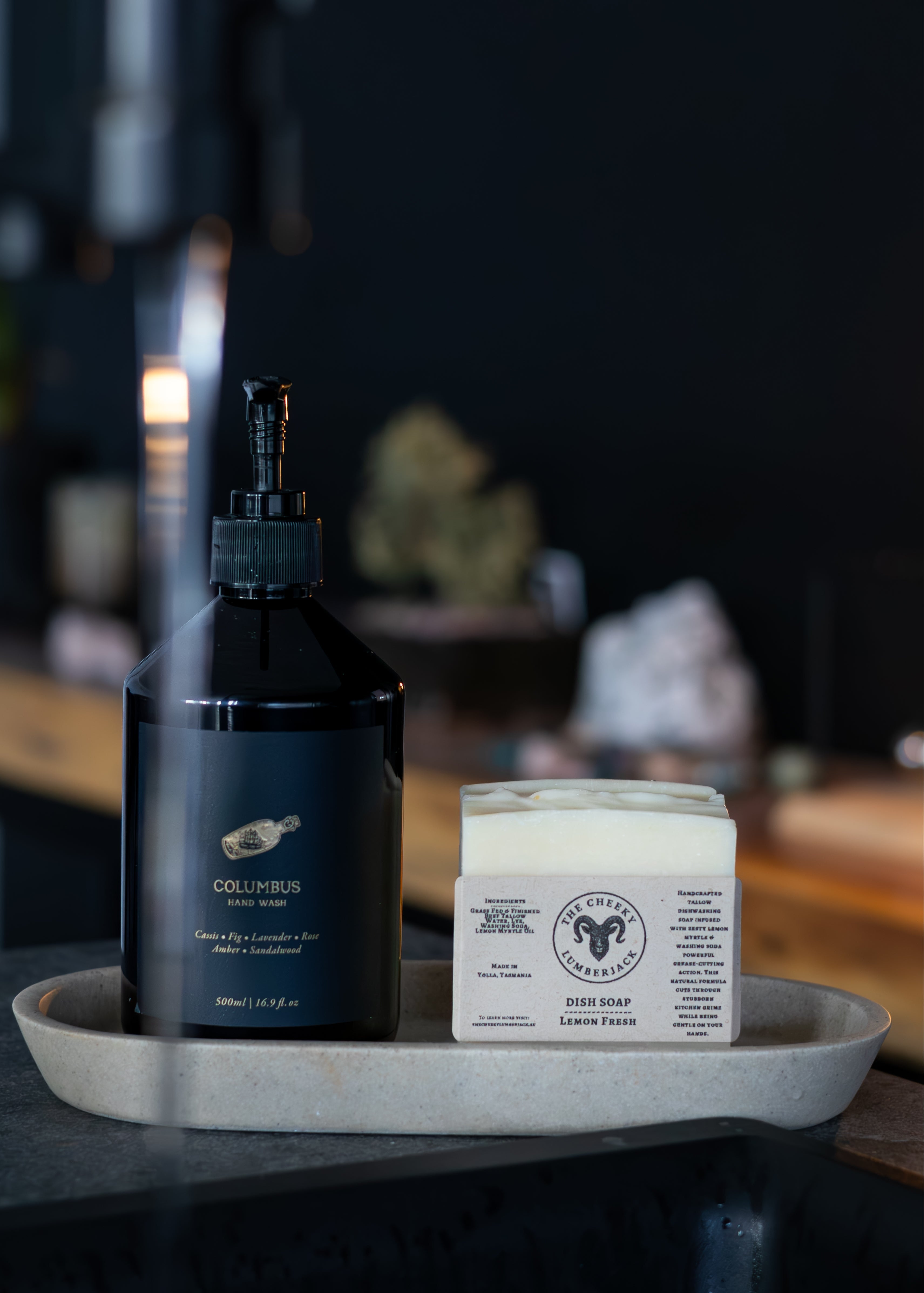 Black bottle and white bar of soap on a gray tray with a blurred background