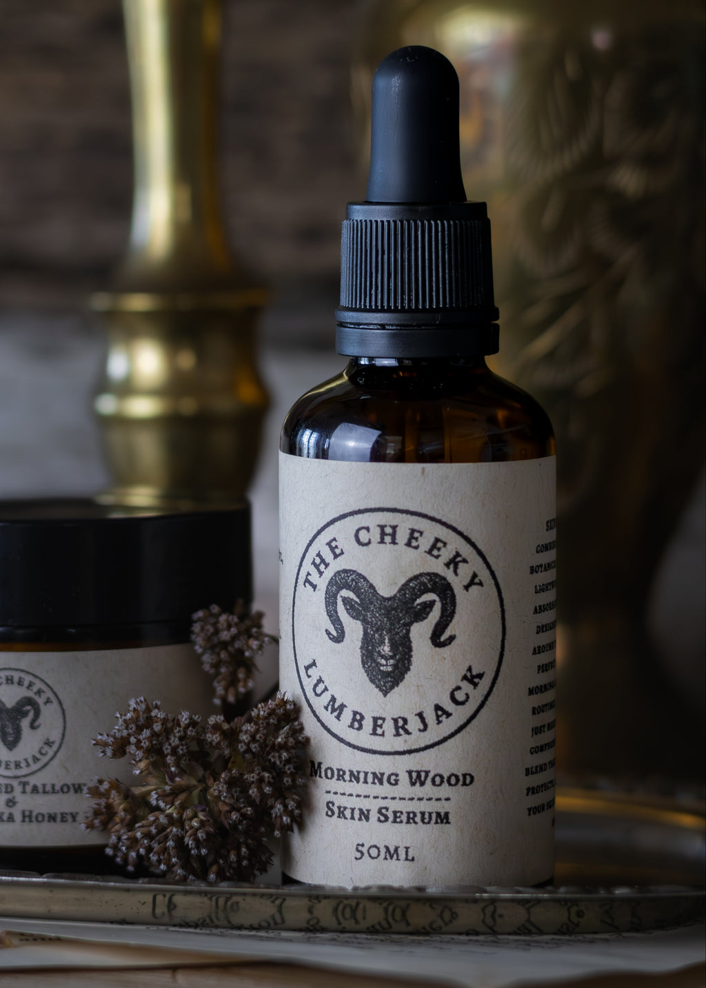 Bottle of 'The Cheeky Lumberjack' skin serum and a jar on a rustic surface with a blurred background.