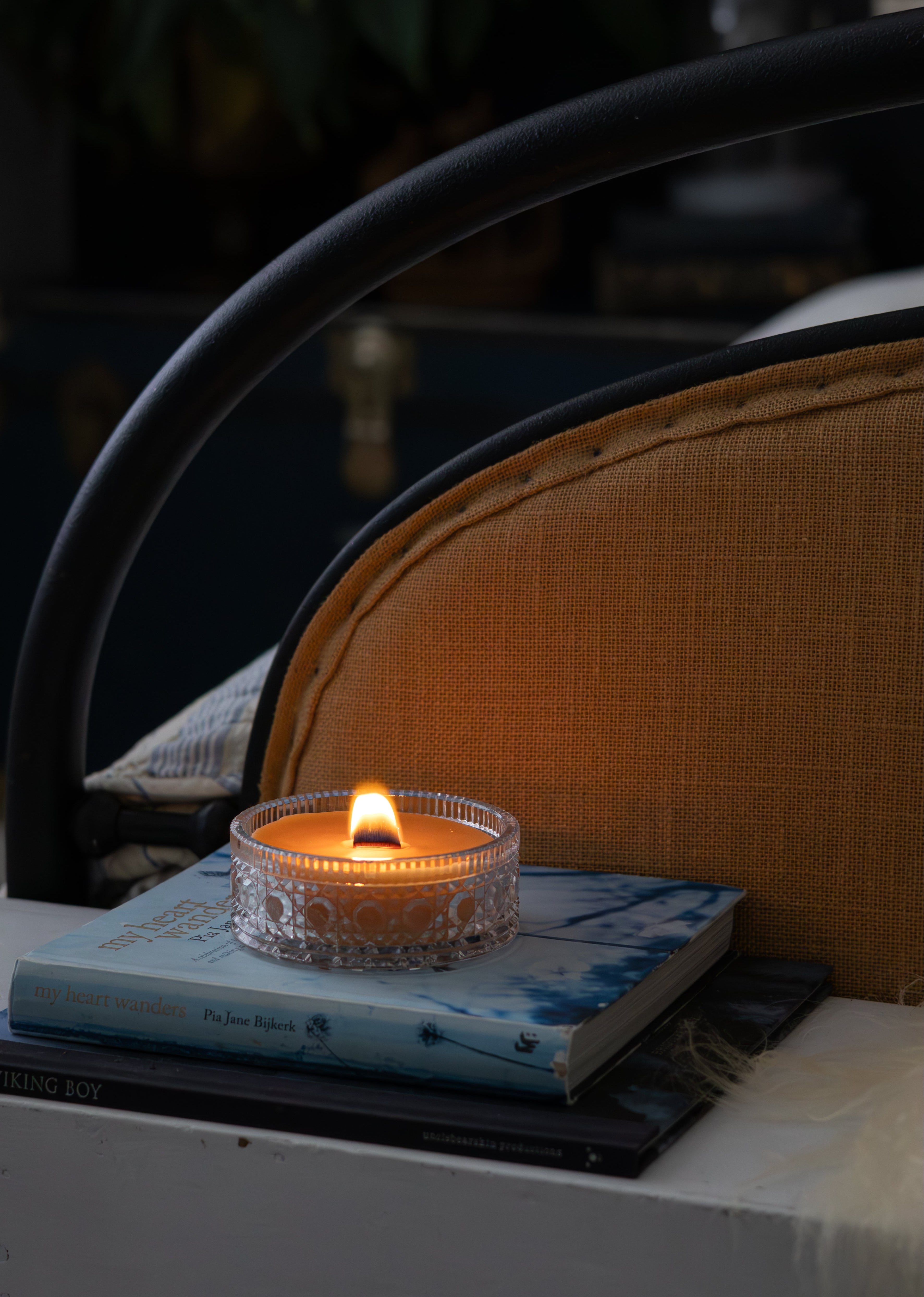 Tasmanian Beeswax Candle in a vintage crystal holder on a book with a blurred background